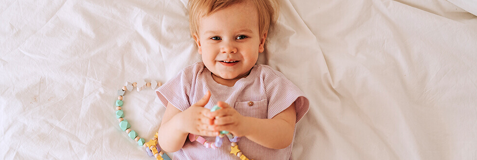 niedliches Baby mit personalisierter Lernkette aus Holzperlen