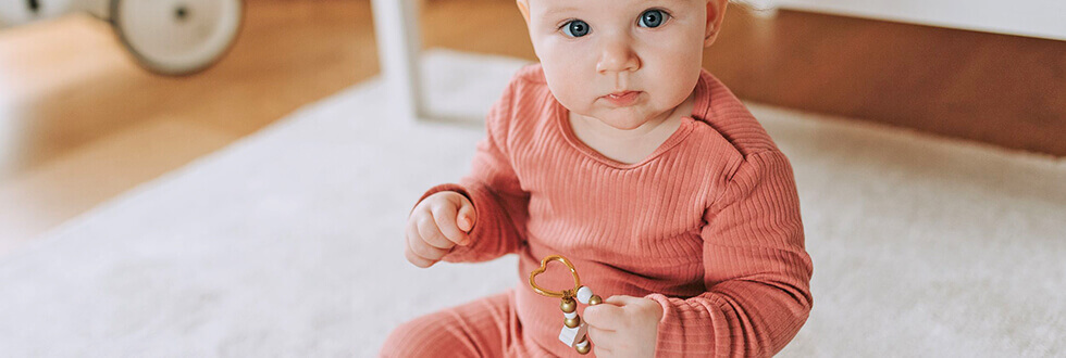 niedliches Baby mit personalisiertem Schlüsselanhänger aus Holzperlen